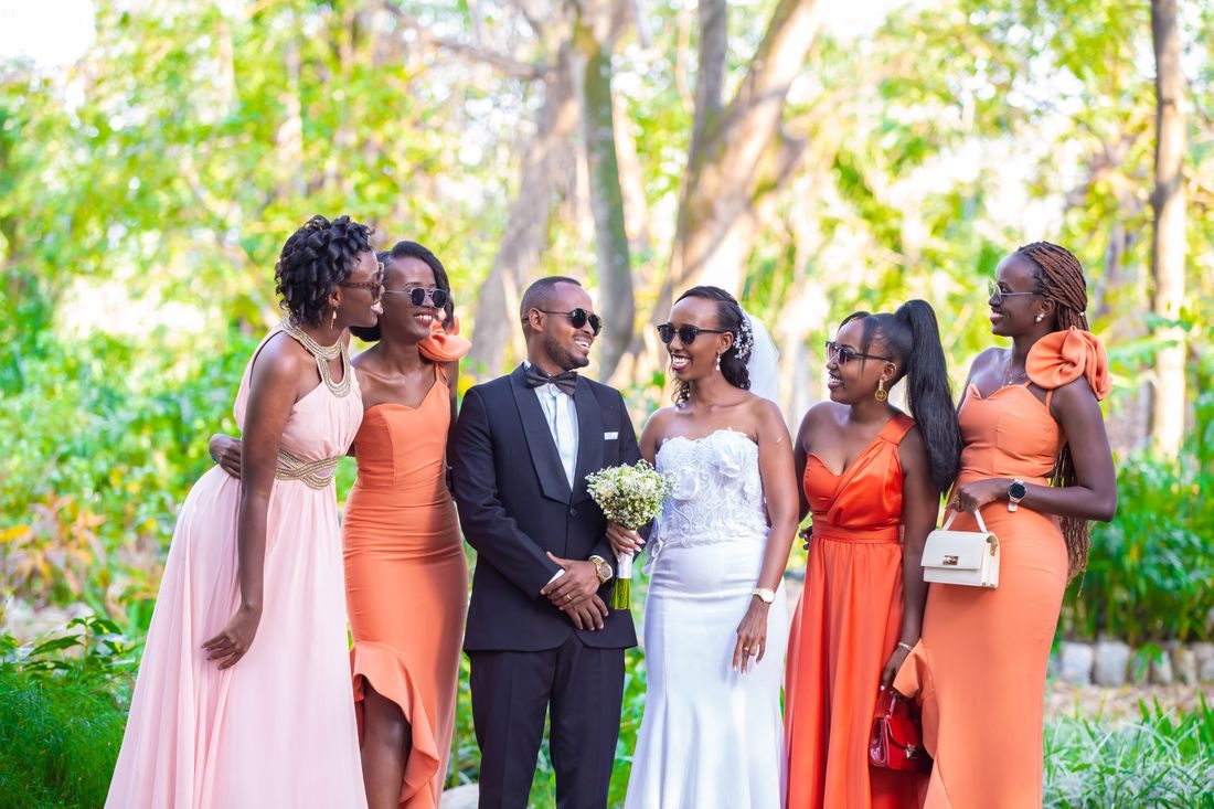 Cheerful newlyweds standing among their bridesmaids